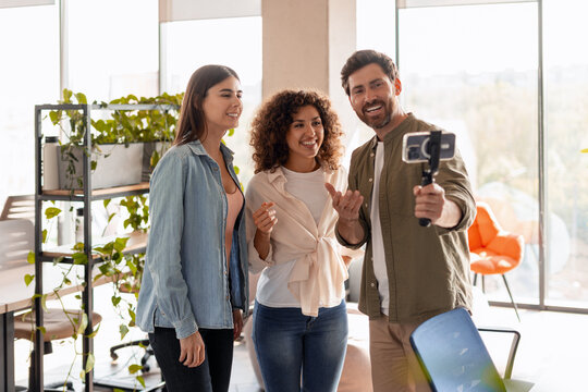 Startup team recording video with smartphone and gimbal in modern office