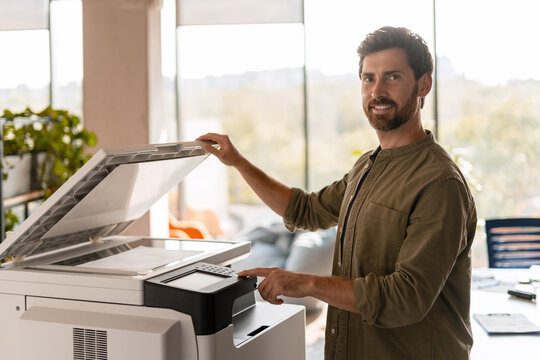 Businessman using a multifunctional printer in the office - Powered by Adobe