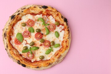 Delicious pizza with tomatoes, olives and basil on pink table, top view. Space for text