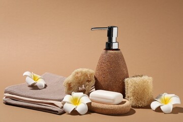 Folded waffle towels, plumeria flowers and spa products on light brown background, closeup