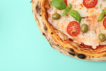 Delicious pizza with tomatoes, basil and olives on turquoise background, top view. Space for text