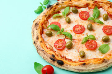 Delicious pizza with tomatoes, basil and olives on turquoise background, closeup. Space for text