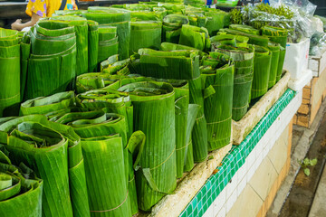 Rolled banana leaves neatly stacked for sale at a local market in Phuket, Thailand. Thai market, culinary culture, organic farming. Sustainable food packaging