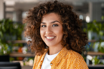 Young businesswoman smiling in modern office with curly hair