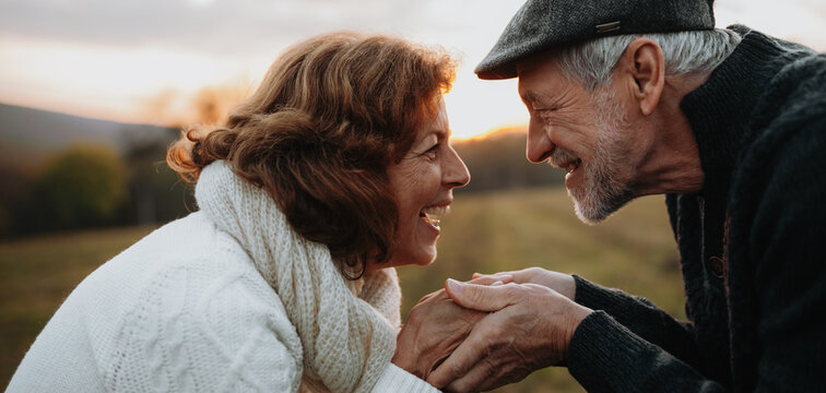 Senior couple holding hands, standing face to face.