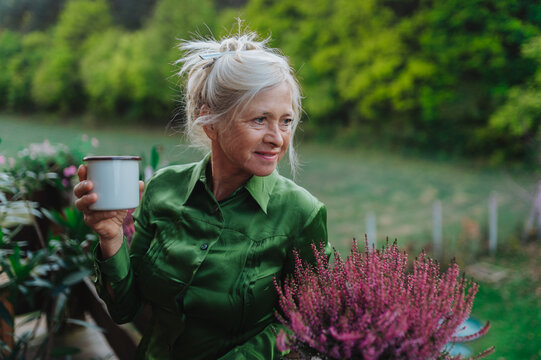 Senior woman standing terrace and drinking coffee.