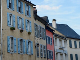 Naklejka premium Quaint buildings featuring blue shutters and colorful facades line the street in a tranquil French town