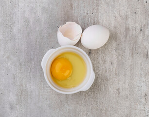 White eggs with broken egg over grey background
