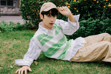 Young male lounging in casual outfit on grass.