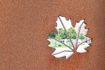 The leaf-shaped cutout in the rusted metal sheet offers an artistic touch that frames the cityscape...