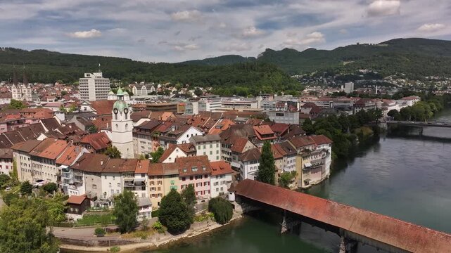 aerial - old wooden bridge crosses river aare beside clock tower in olten solothurn switzerland