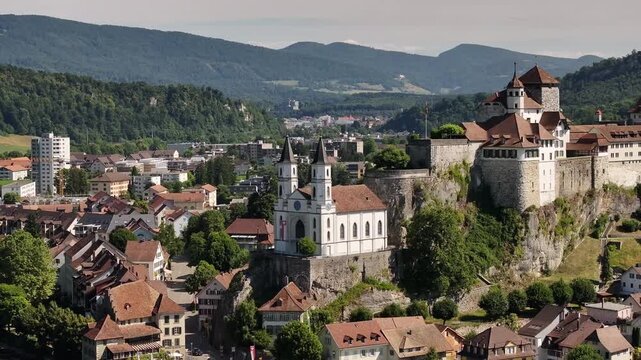 aerial - twin tower church and aarburg castle stand on rocky cliff in solothurn switzerland
