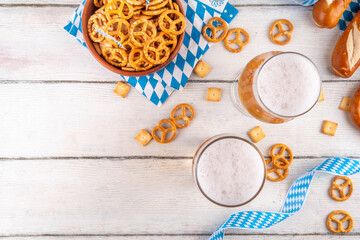 Oktoberfest greeting card background with two beer glasses, salted snack and pretzels. Oktoberfest bar, cafes menu on white wooden table, with checkered napkin and decor in Oktoberfest holiday style