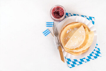 Traditional German, Bavarian pancakes Pfannkuchen for Oktoberfest brunch with checkered napkin and decor in Oktoberfest holiday style, with jams for fillings on white table