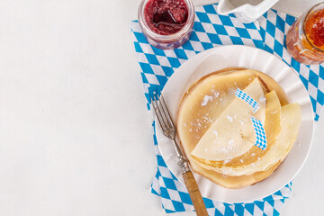 Traditional German, Bavarian pancakes Pfannkuchen for Oktoberfest brunch with checkered napkin and decor in Oktoberfest holiday style, with jams for fillings on white table