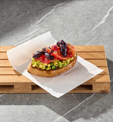Salmon and avocado bruschetta, bright natural light, overhead composition on marble and wooden board