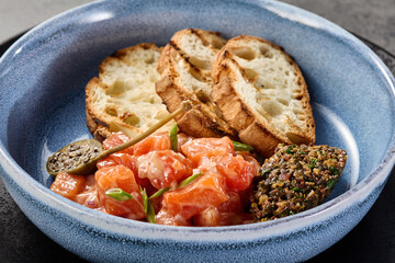 Salmon tartare with ciabatta slices and olive tapenade, rustic bright overhead composition