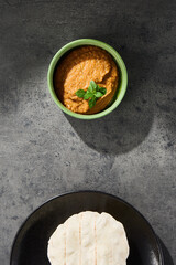 Eggplant hummus dip under bright lighting, minimal overhead composition with pita bread