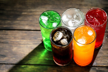 Soft drinks and fruit juice mixed with soda high in sugar have a negative effect on physical health. on the table wood.