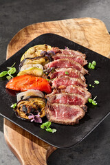 Roast beef slices with grilled vegetables, moody lighting, overhead composition