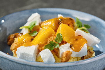 Biscuit dessert with mango, passion fruit and meringue in bright rustic closeup composition