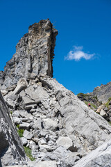A lone woman hiker is climbing up a rocky face while hiking in the French Alps.