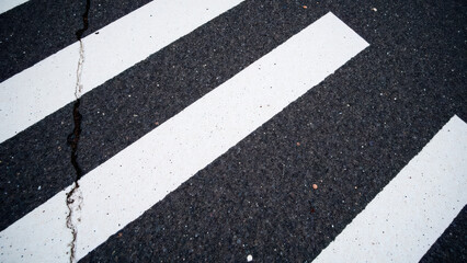 Fototapeta premium Zebra crossing on asphalt road with white stripes and dark surface, showcasing urban infrastructure and pedestrian safety