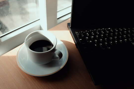 Cup of coffee and laptop on vintage iron table.