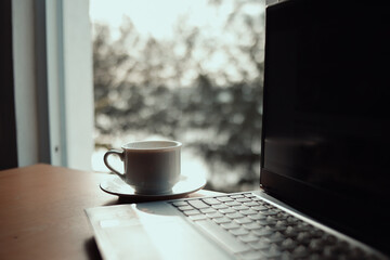 Cup of coffee and laptop on vintage iron table.