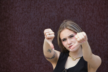 blonde woman with light eyes, young and beautiful, lowers the thumb of her two hands and makes the...
