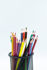 Fototapeta premium Colorful pencils standing in a black metal pencil holder on a white background