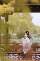 Young woman in traditional clothing by peaceful pond.