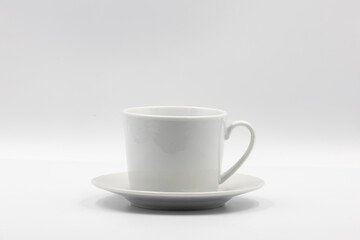 White porcelain coffee cup standing on matching saucer on white background