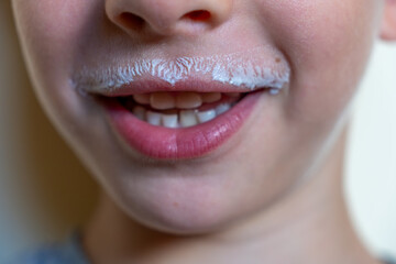 Close up of a cheerful child with a milk mustache or milkstache, savoring a refreshing glass of...