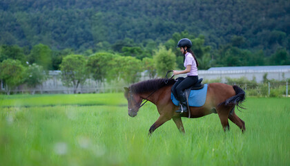 Person riding horse through lush green field with forested hill in background, enjoying peaceful moment