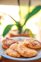 A cozy homemade breakfast featuring traditional syrniki (cottage cheese pancakes) served with butter and sausage. Set in a warm, rustic home environment with soft morning light, this comforting meal e