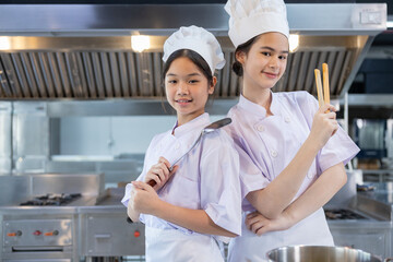 Two young chefs smiling in professional kitchen
