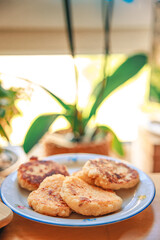 A cozy homemade breakfast featuring traditional syrniki (cottage cheese pancakes) served with butter and sausage. Set in a warm, rustic home environment with soft morning light, this comforting meal e