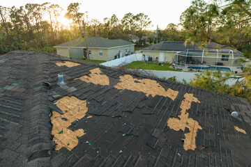Damaged house roof with missing shingles after hurricane Ian in Florida. Consequences of natural...