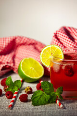 Refreshing berry drink in vertical format, styled with fruit and herbs on gingham cloth. Close-up.