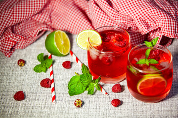 Simple drink with citrus and herbs. Mint and lime cocktail on a red gingham cloth. Cozy homemade drink scene.