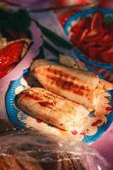 A vibrant outdoor barbecue scene with people grilling shashlik and marinated vegetables over an open fire. Juicy skewered meat and colorful vegetables sizzle on the mangal, surrounded by friends enjoy