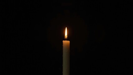 Fototapeta premium Single candle burning brightly against black background for holiday event