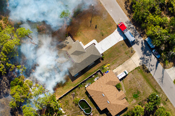 Wildfire rages near homes in Florida town while fire trucks and emergency crew combat the advancing...