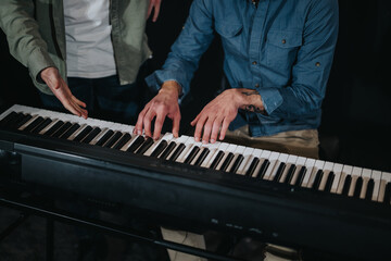 Collaboration on a musical piece as two individuals hands play on a keyboard.