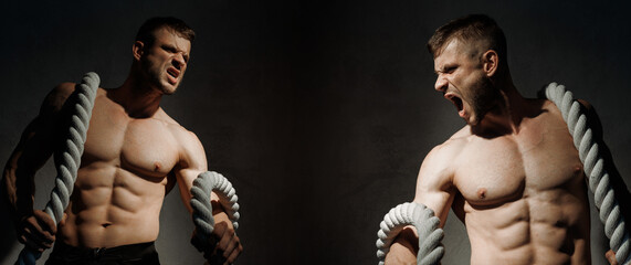 Muscular model sports young man on dark background. Guy with the rope is doing a workout. athlete...