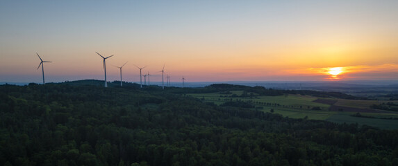 Last rays of light over the wind-turbine-dotted mountains and forest