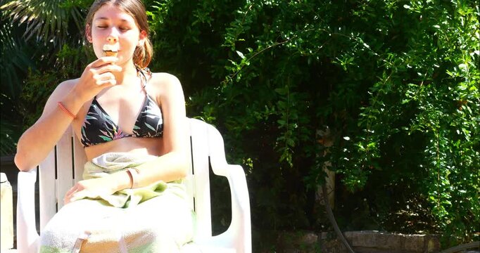 Pretty teenage girl by the pool devouring an ice cream cone
