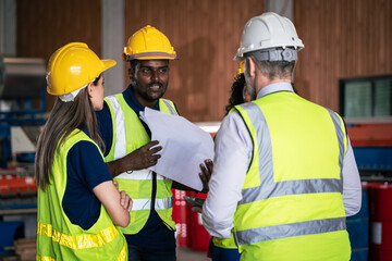 Diverse team of industrial workers wearing safety helmets and reflective vests receiving...