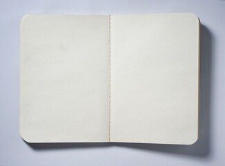 Opened empty book with white plain paper isolated on horizontal copy spaced white background from top angle view.
